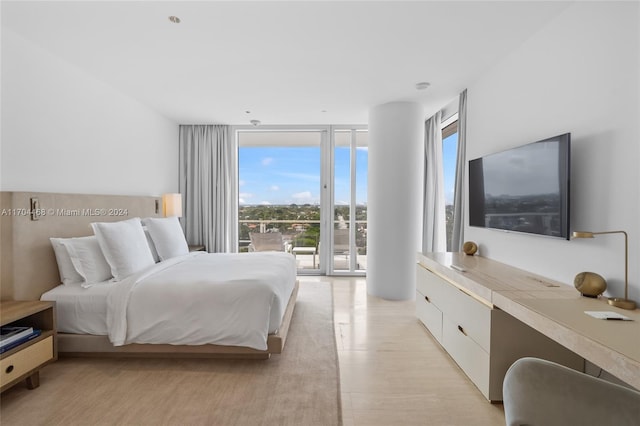 bedroom with multiple windows, light hardwood / wood-style flooring, and expansive windows