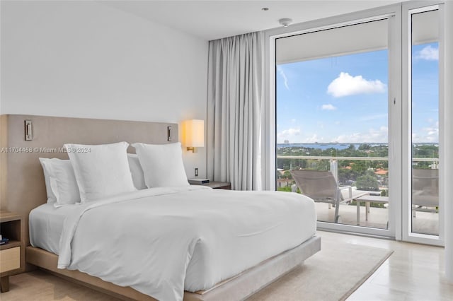 bedroom with access to exterior, light hardwood / wood-style floors, and multiple windows