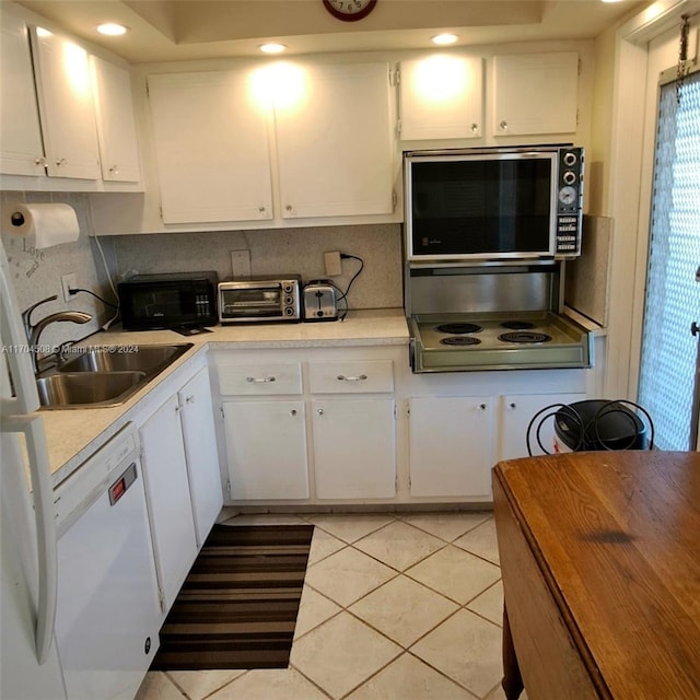 kitchen with stainless steel cooktop, white dishwasher, sink, light tile patterned floors, and white cabinets