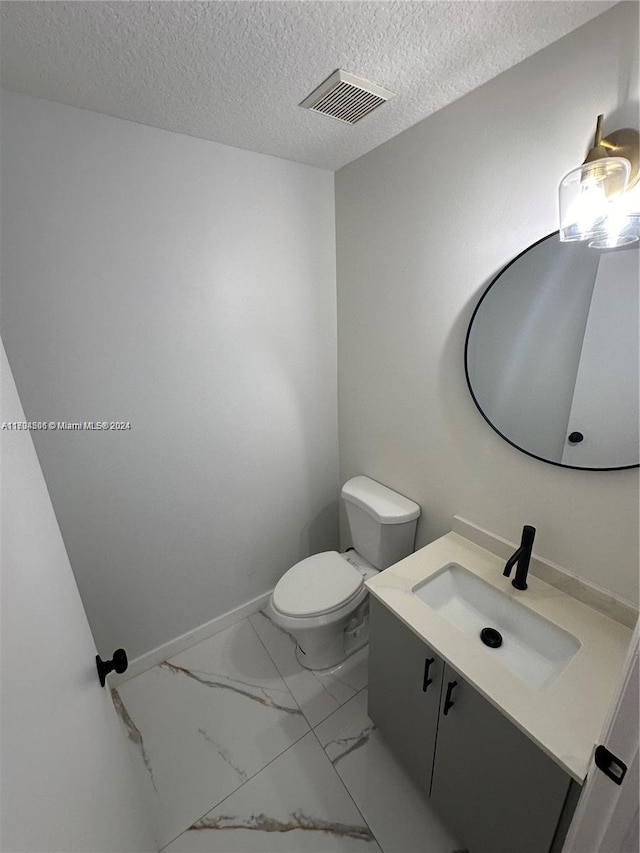 bathroom with vanity, toilet, and a textured ceiling