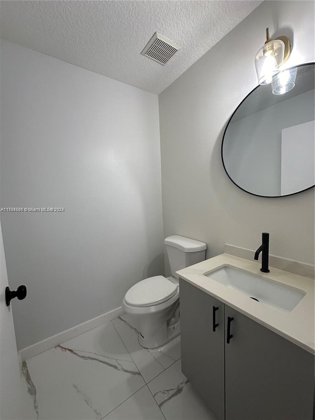 bathroom featuring vanity, a textured ceiling, and toilet