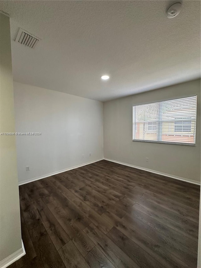 empty room featuring a textured ceiling and dark wood-type flooring