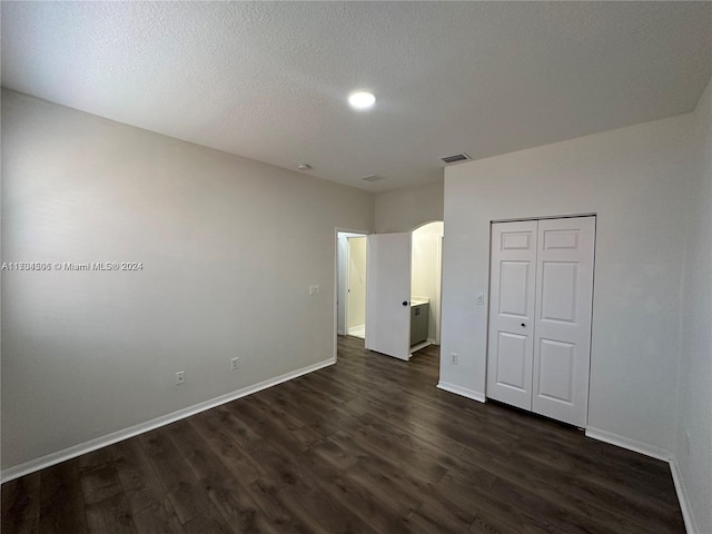 unfurnished bedroom featuring dark hardwood / wood-style flooring, a textured ceiling, and a closet