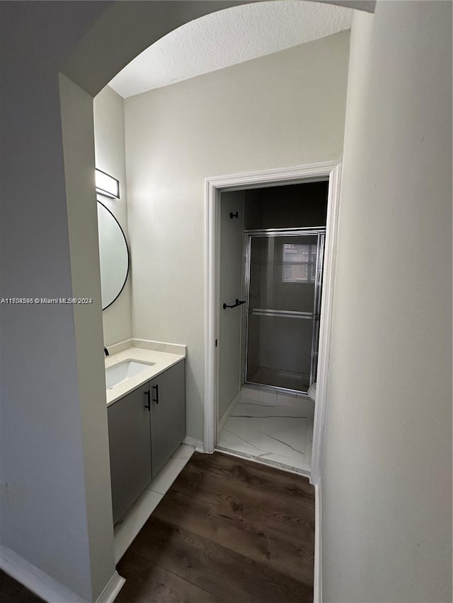 bathroom featuring hardwood / wood-style floors, vanity, walk in shower, and a textured ceiling