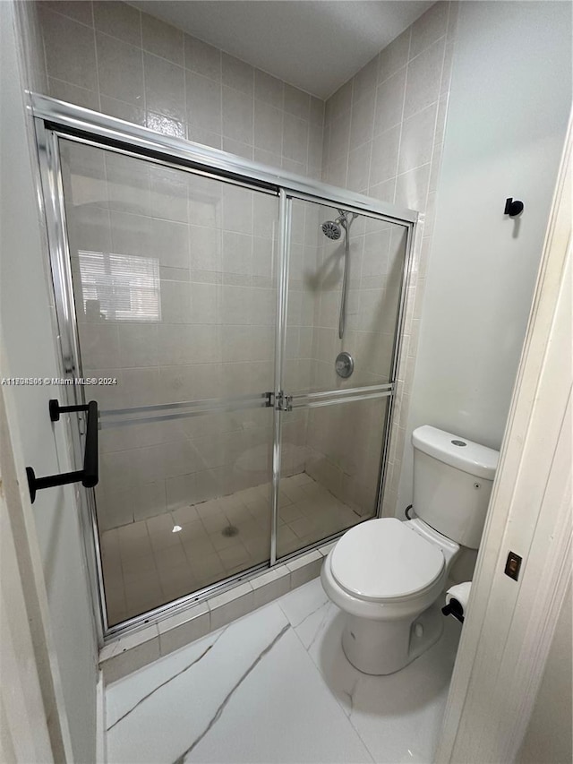 bathroom with toilet and an enclosed shower