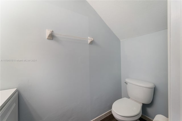 bathroom with vanity, toilet, and lofted ceiling