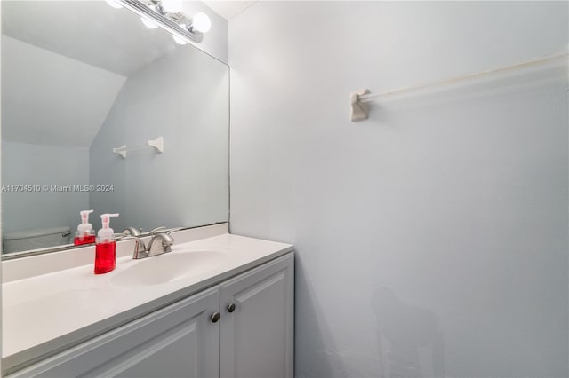 bathroom with toilet, vanity, and vaulted ceiling