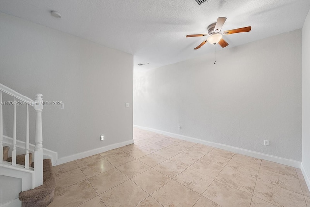 empty room featuring light tile patterned flooring, ceiling fan, and a textured ceiling