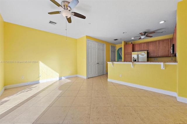 kitchen with kitchen peninsula, stainless steel refrigerator with ice dispenser, a kitchen breakfast bar, ceiling fan, and light tile patterned floors