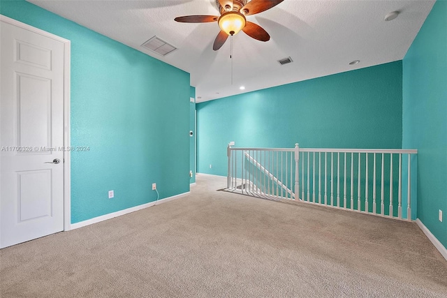 empty room with ceiling fan, carpet, and a textured ceiling