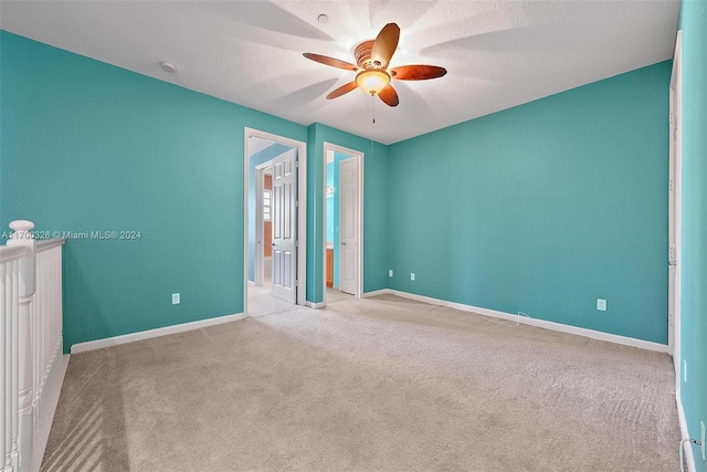 unfurnished bedroom with a textured ceiling, light colored carpet, and ceiling fan