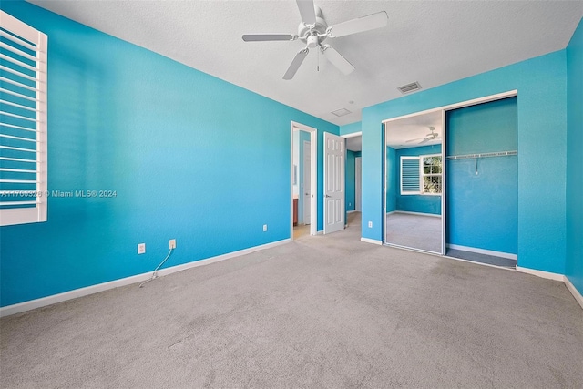 unfurnished bedroom featuring a textured ceiling, carpet floors, a closet, and ceiling fan