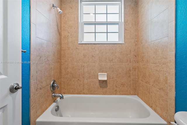 bathroom featuring tiled shower / bath combo and toilet