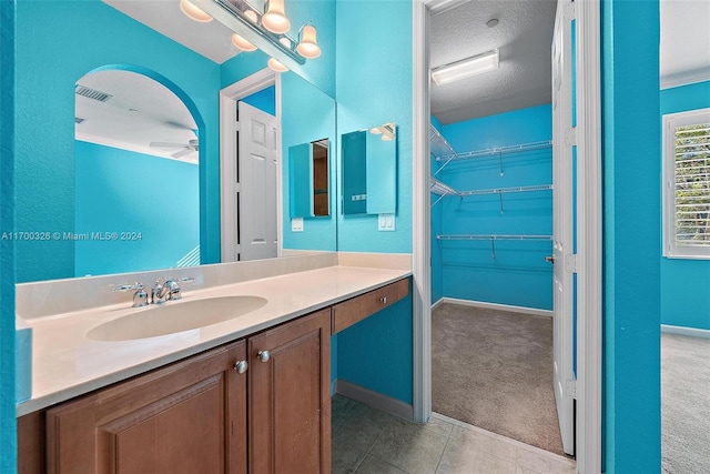 bathroom with vanity, a textured ceiling, ceiling fan, and tile patterned flooring