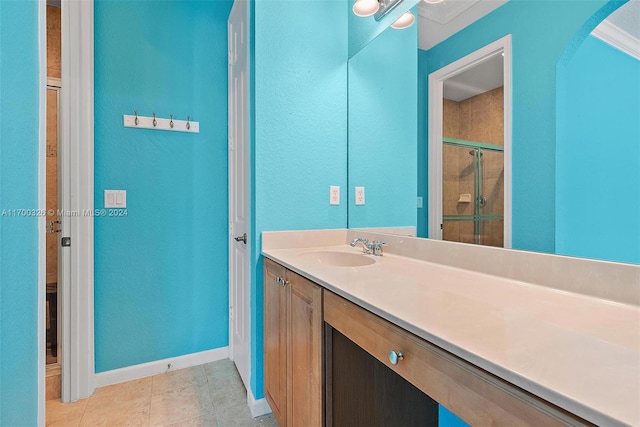 bathroom with tile patterned flooring, vanity, a shower with door, and ornamental molding