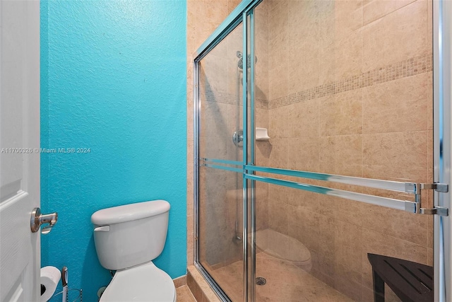 bathroom with toilet and a shower with door