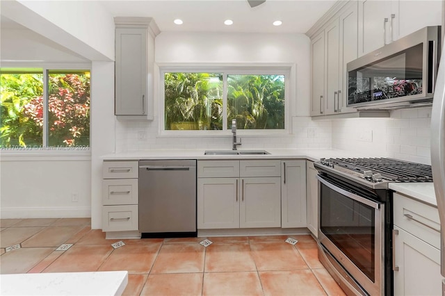 kitchen featuring appliances with stainless steel finishes, light tile patterned floors, a wealth of natural light, and sink