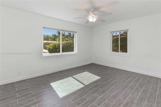 spare room with ceiling fan, a healthy amount of sunlight, and dark wood-type flooring