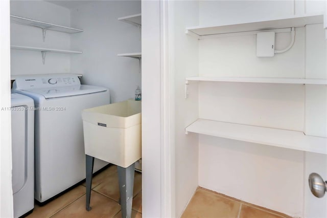 laundry area featuring washing machine and clothes dryer, sink, and light tile patterned flooring