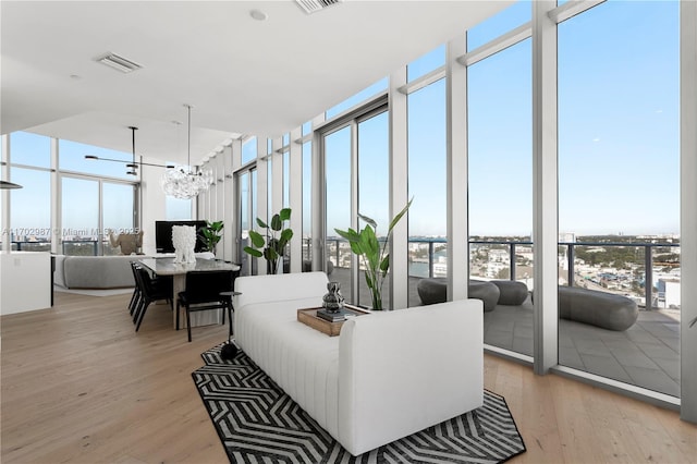 living room with light hardwood / wood-style flooring, expansive windows, and a chandelier