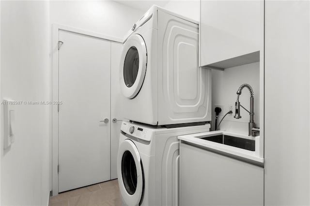 laundry area featuring sink, light tile patterned floors, and stacked washer / dryer