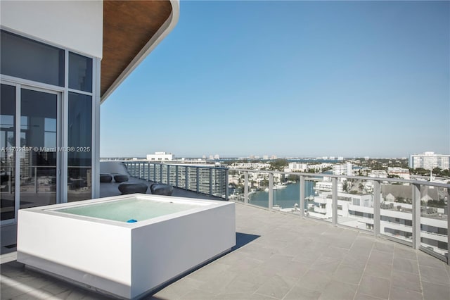 view of patio / terrace featuring a jacuzzi, a water view, and a balcony