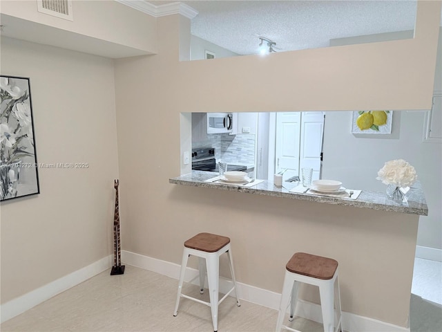 kitchen with electric range, light stone countertops, a textured ceiling, a kitchen bar, and kitchen peninsula