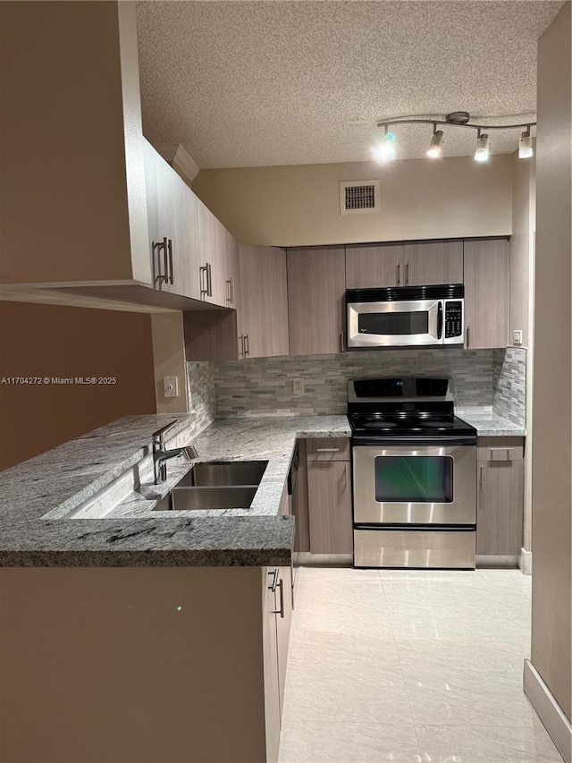 kitchen featuring decorative backsplash, appliances with stainless steel finishes, a textured ceiling, sink, and dark stone countertops