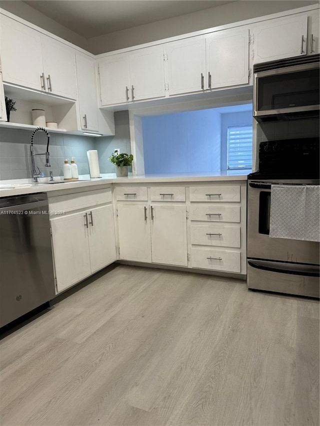 kitchen featuring white cabinetry, sink, stainless steel appliances, tasteful backsplash, and light hardwood / wood-style floors