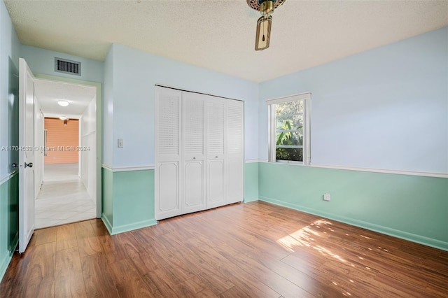 unfurnished bedroom featuring a textured ceiling, hardwood / wood-style flooring, and a closet