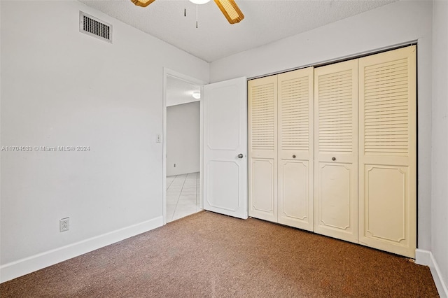 unfurnished bedroom with carpet, ceiling fan, a textured ceiling, and a closet