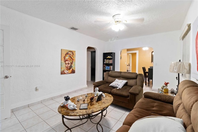 living room featuring ceiling fan, light tile patterned flooring, and a textured ceiling