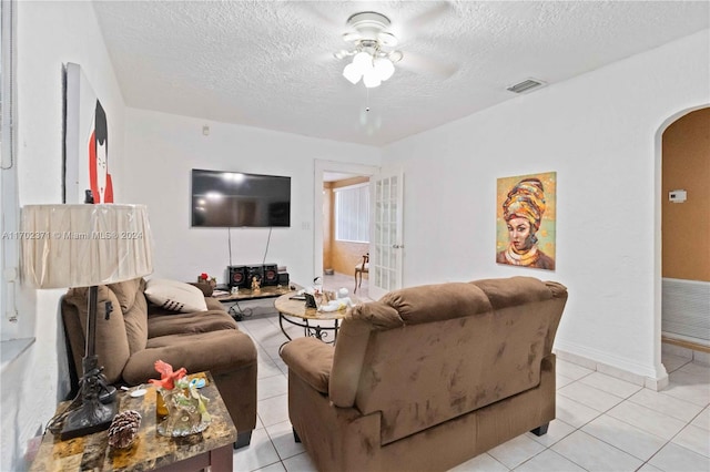 living room with light tile patterned floors, a textured ceiling, and ceiling fan