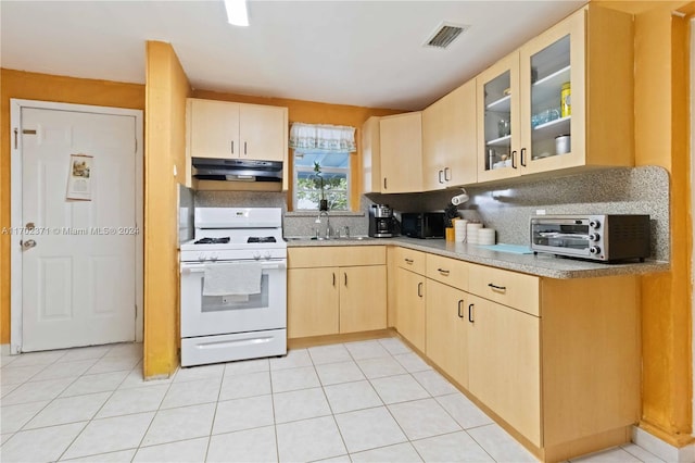 kitchen with light brown cabinets, sink, decorative backsplash, light tile patterned floors, and white range with gas stovetop