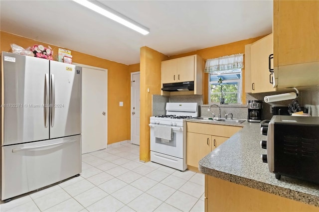 kitchen with backsplash, white range with gas cooktop, sink, light brown cabinets, and stainless steel refrigerator