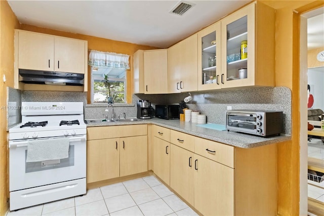 kitchen with white gas range, light brown cabinets, sink, backsplash, and light tile patterned floors