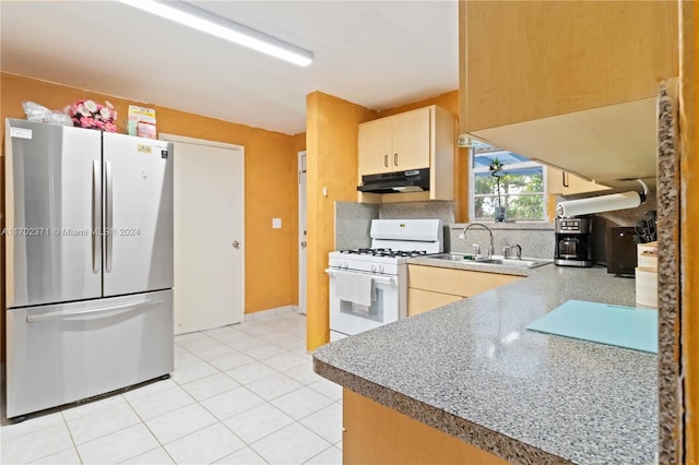 kitchen featuring stainless steel refrigerator, sink, light brown cabinets, white range with gas stovetop, and light tile patterned floors