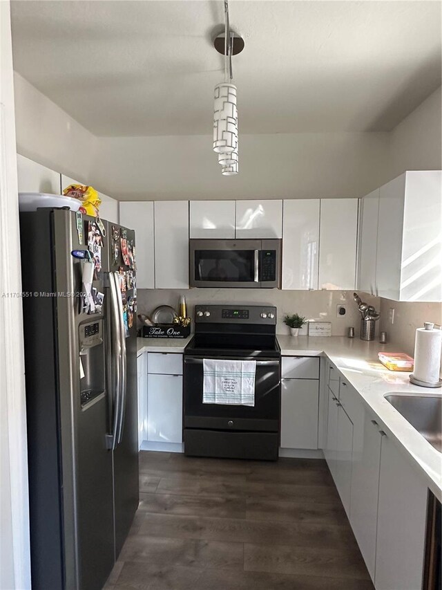 kitchen with appliances with stainless steel finishes, backsplash, dark wood-type flooring, decorative light fixtures, and white cabinets