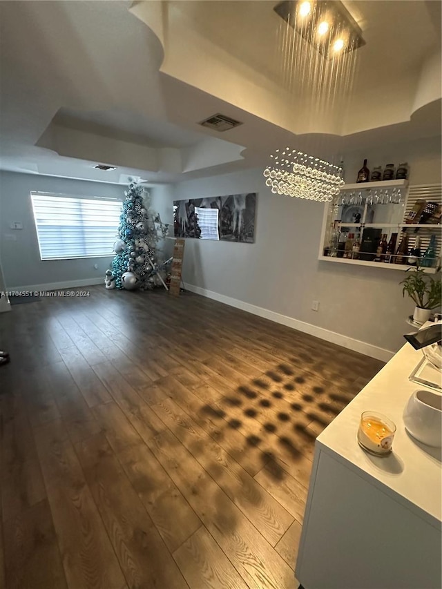 living room featuring a chandelier, dark hardwood / wood-style floors, and a tray ceiling