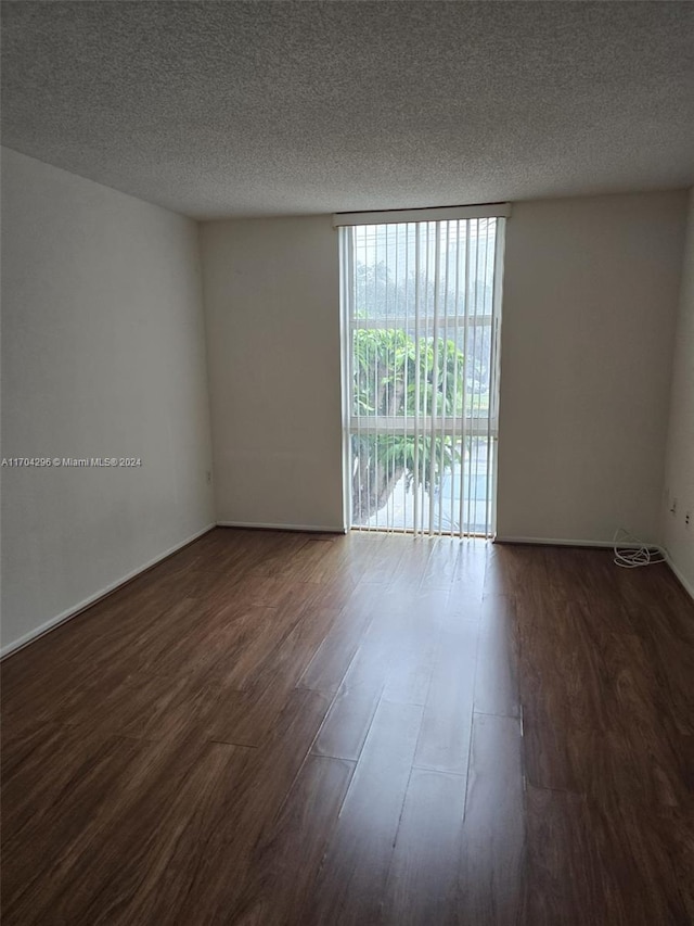 empty room featuring a textured ceiling and dark hardwood / wood-style floors