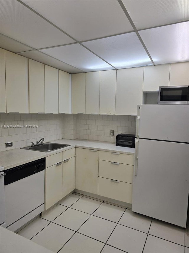 kitchen with a paneled ceiling, white appliances, backsplash, sink, and light tile patterned floors