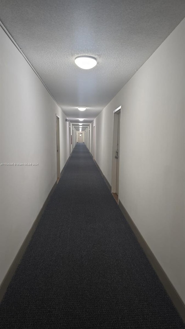 hallway with carpet flooring and a textured ceiling