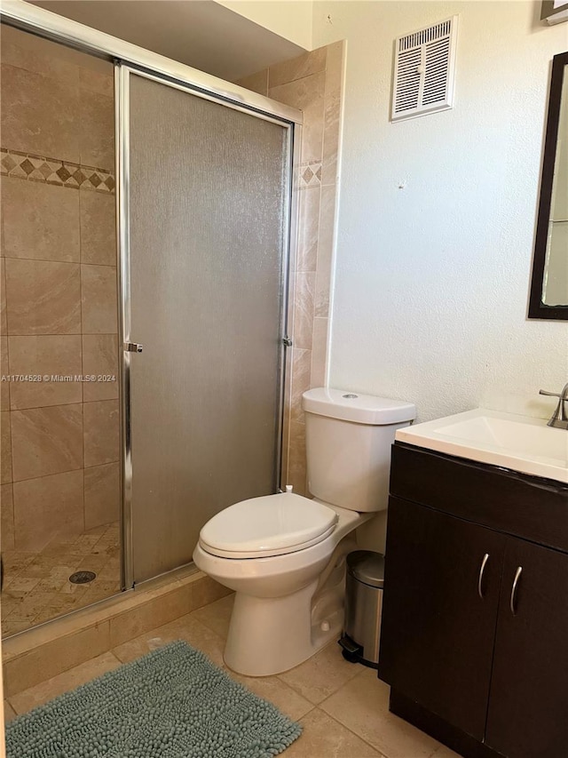 bathroom featuring tile patterned flooring, vanity, toilet, and an enclosed shower