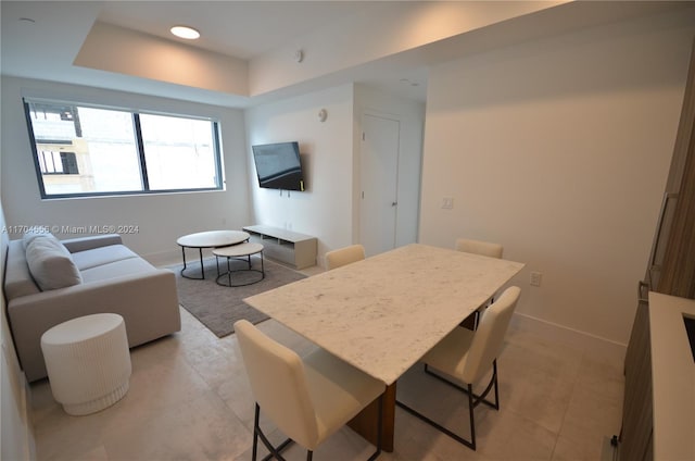 dining area with light tile patterned floors and a tray ceiling