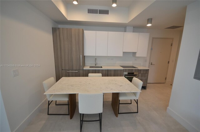 239 SW 9th St Unit 1603, Miami, FL 33130 - kitchen with a tray ceiling, a kitchen breakfast bar, modern cabinets, white cabinets, and stainless steel oven