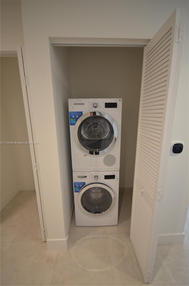 laundry area featuring light tile patterned floors and stacked washer and clothes dryer