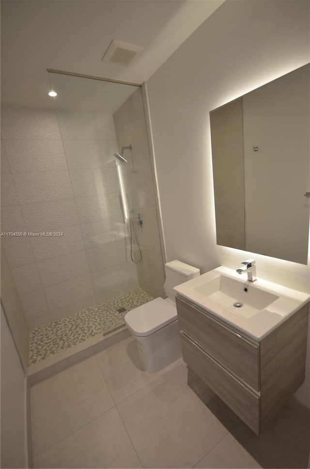 bathroom featuring tile patterned floors, vanity, toilet, and a tile shower