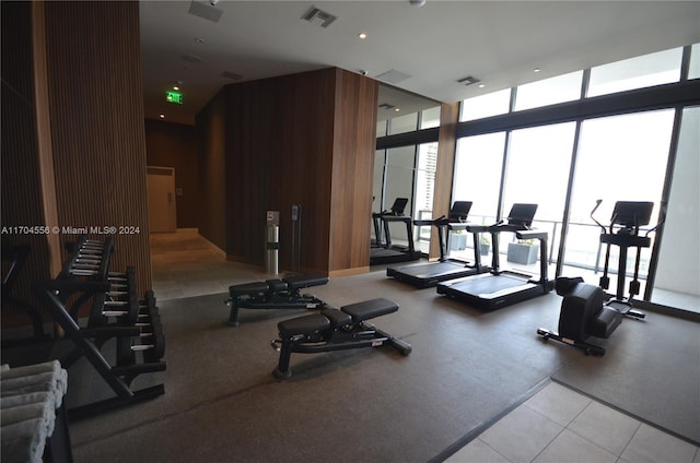 exercise room featuring a wall of windows and wood walls