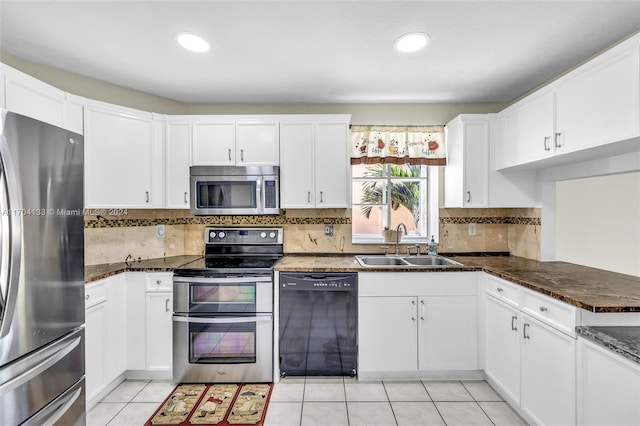 kitchen featuring white cabinetry, sink, stainless steel appliances, dark stone countertops, and light tile patterned flooring