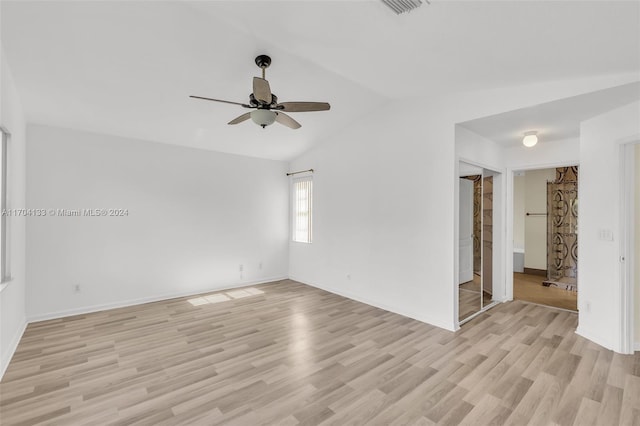 empty room with ceiling fan, light wood-type flooring, and vaulted ceiling